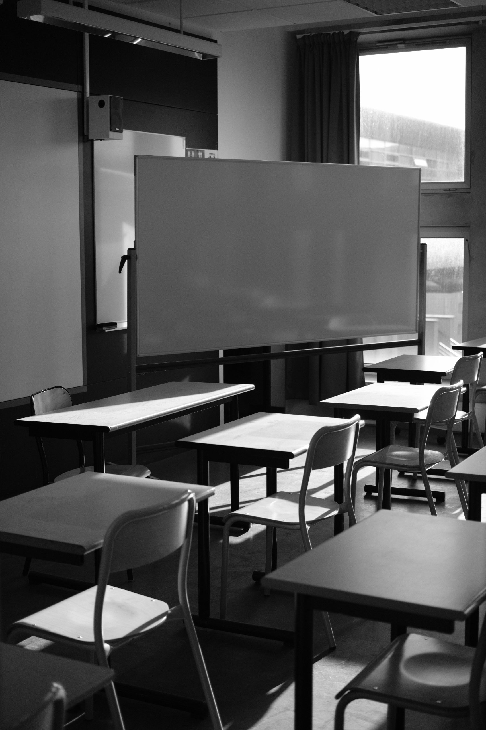 Salle de classe vide avec rangées de pupitres, photo en noir et blanc